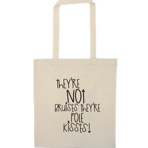 May include: A cream-coloured tote bag featuring the text "THEY'RE NOT BRUISES THEY'RE POLE KISSES!" in black. The bag has a rectangular design with a handle, ideal for carrying items.