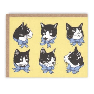May include: Greeting card featuring six black and white cat illustrations with blue bow ties on a yellow background. The cats are in various poses, with a brown border.