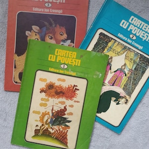 May include: Three softcover books titled Cartea cu Povesti, numbered 1, 2, and 3, published by Editura Ion Creanga. The green book features a figure with a bow and arrow, the blue book shows illustrated figures, and the red book depicts animal characters.