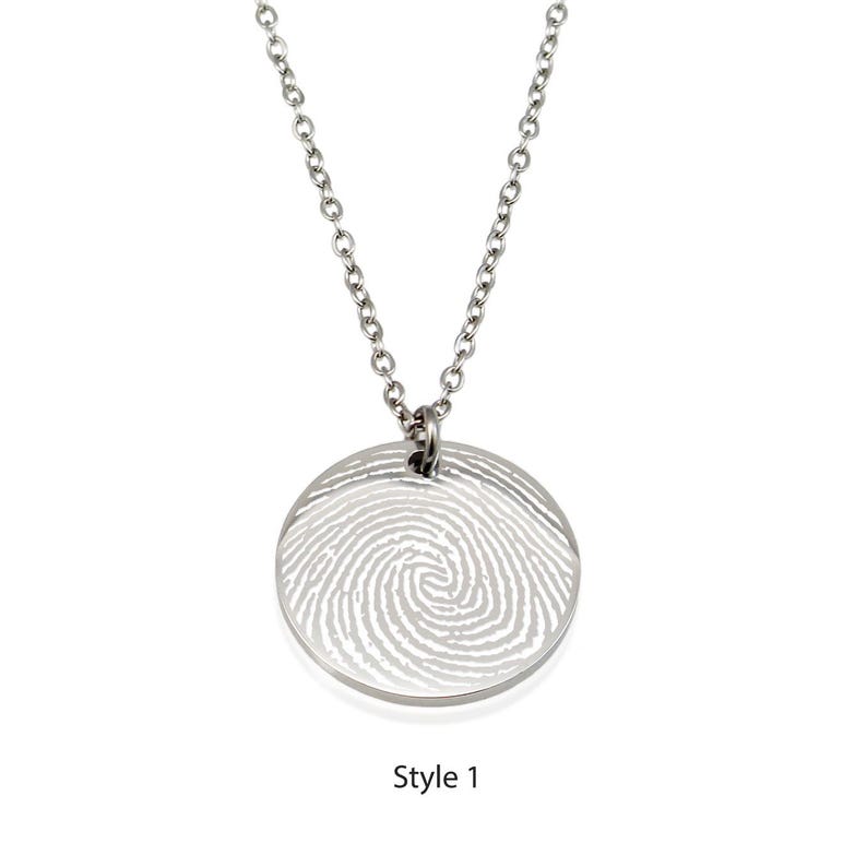 May include: A silver necklace with a round pendant featuring a fingerprint design. The pendant is engraved with a fingerprint pattern. The necklace is a great way to memorialize a loved one.