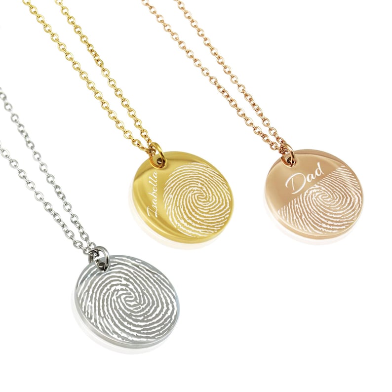 May include: Three silver necklaces with round pendants featuring fingerprint designs. The pendants are engraved with the names "Isabella", "Dad", and a blank space.
