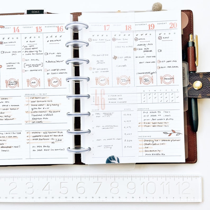 Peut inclure: Un agenda hebdomadaire avec une couverture en cuir marron et un reliure &agrave; anneaux argent&eacute;s. L'agenda a une mise en page quotidienne avec des sections pour les objectifs, les courses, les vitamines, les pas, la cr&eacute;ativit&eacute; et les arriv&eacute;es. L'agenda est ouvert &agrave; la semaine du 14 juillet au 20 juillet.