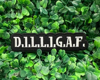 May include: A black rectangular patch with white text that reads "D.I.L.L.I.G.A.F." The patch is set against a background of vibrant green foliage. The patch is likely an accessory for clothing or bags.