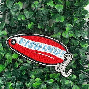 May include: Red and white embroidered patch shaped like a fishing lure with the word "FISHING!" in blue lettering and a silver hook.