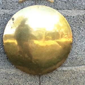 May include: A round, shiny, gold-colored metal plate hanging on a wall.