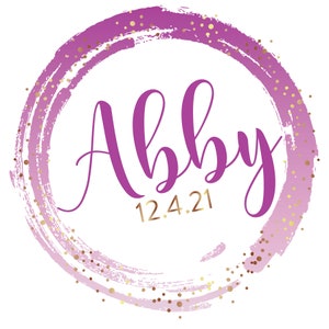 May include: A pink and gold circle with a brushstroke design and gold glitter. The name "Abby" is written in purple script inside the circle, with the date "12.4.21" written in gold below it.