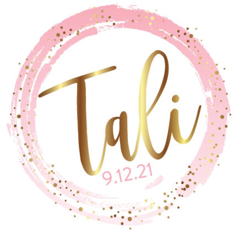 May include: A pink and gold circle with the name "Tali" written in gold script and the date "9.12.21" below it.