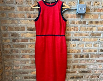 May include: A sleeveless red dress with a black trim around the neckline and waist.