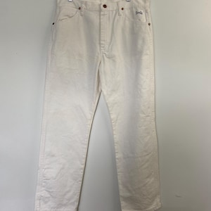 Op de afbeelding: Een paar witte rechte jeans met een klein bruin label met de tekst "Shro" op de rechter achterzak.
