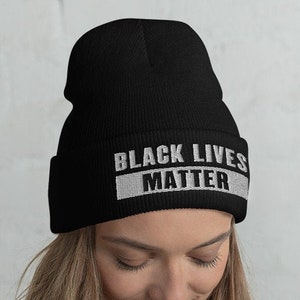 Puede incluir: Gorro negro con las palabras "Black Lives Matter" en letras blancas.