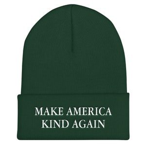 Puede incluir: Un gorro de lana verde oscuro con el texto "MAKE AMERICA KIND AGAIN" en letras blancas.