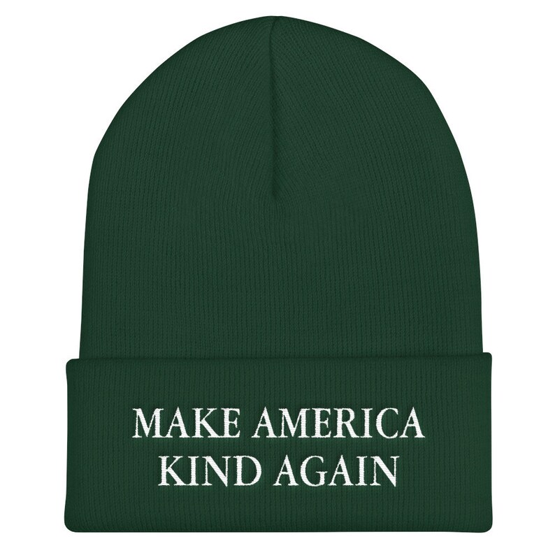 Puede incluir: Un gorro de lana verde oscuro con el texto "MAKE AMERICA KIND AGAIN" en letras blancas.