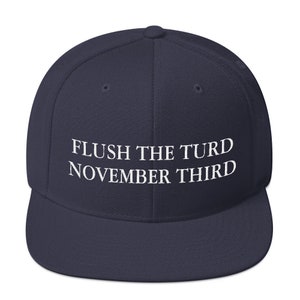 May include: A navy blue baseball cap with the text "FLUSH THE TURD NOVEMBER THIRD" embroidered in white on the front.