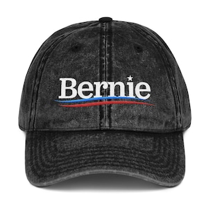 以下が含まれることがあります： 「Bernie」という白い文字と、その下に赤白青のストライプが入った、黒いビンテージスタイルの野球帽。