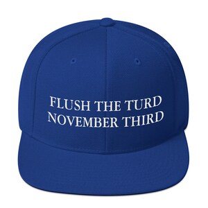 May include: A royal blue baseball cap with white embroidered text that reads "FLUSH THE TURD NOVEMBER THIRD".