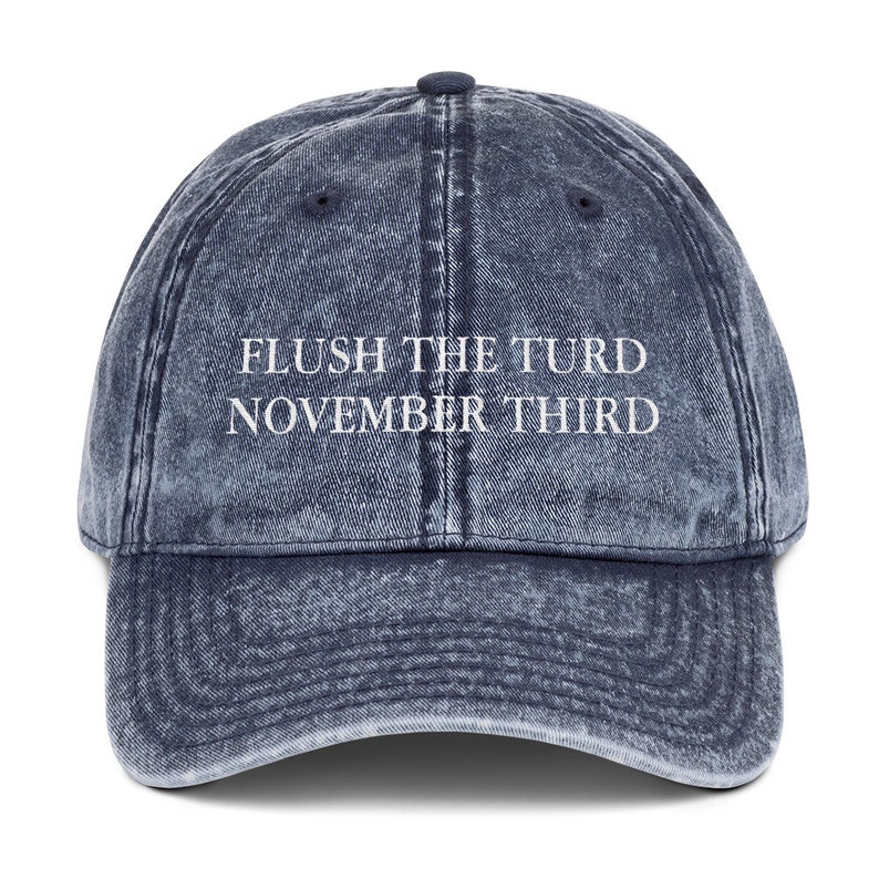May include: A blue denim baseball cap with the text "FLUSH THE TURD NOVEMBER THIRD" embroidered in white.