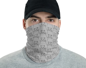 May include: A gray face mask with a repeating pattern of black line drawings of cats. The mask is worn by a person with a black baseball cap.
