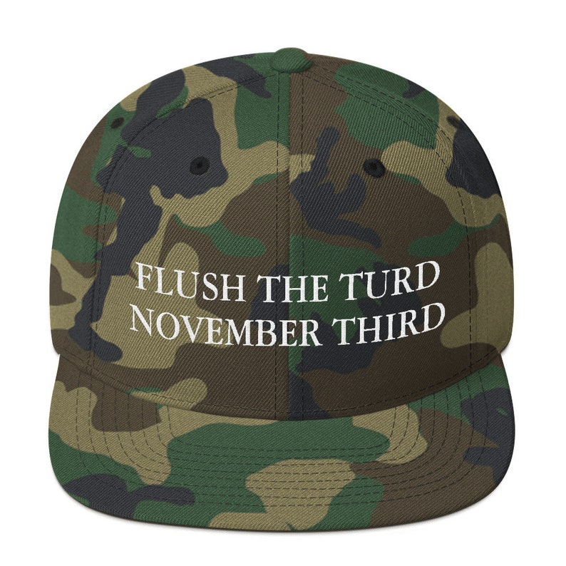 May include: A camouflage-patterned baseball cap with the text "FLUSH THE TURD NOVEMBER THIRD" embroidered in white on the front.