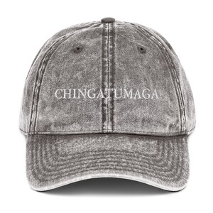 May include: A gray distressed denim baseball cap with the text "CHINGATUMAGA" embroidered in white on the front.