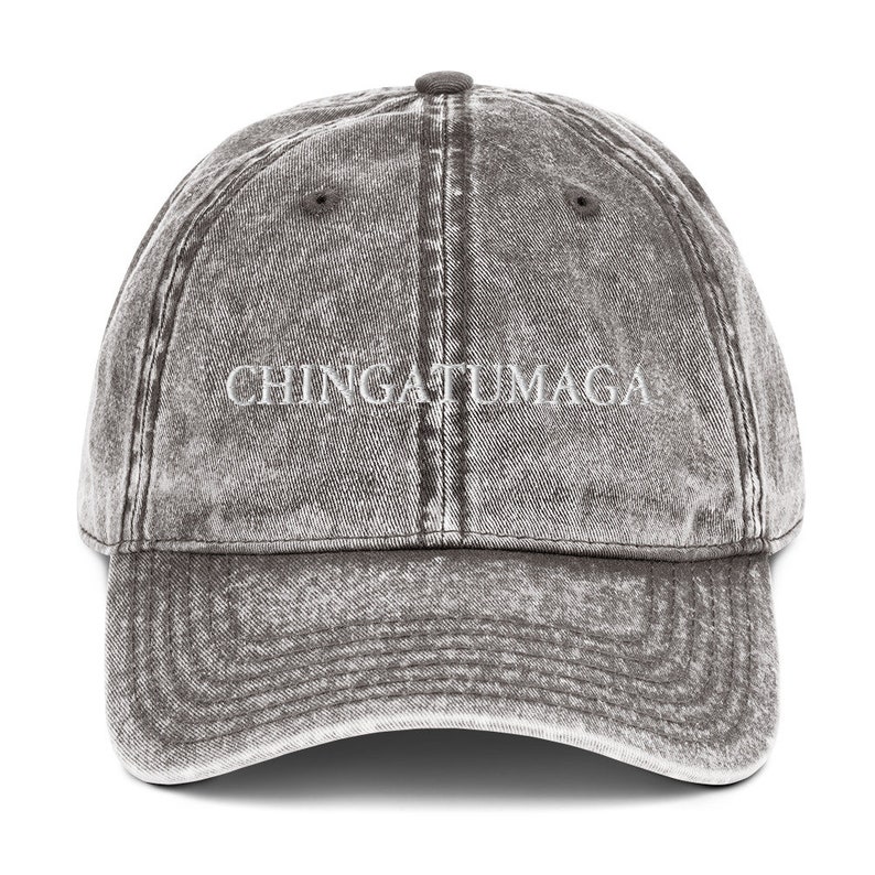 May include: A gray distressed denim baseball cap with the text "CHINGATUMAGA" embroidered in white on the front.