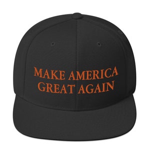 Op de afbeelding: Een zwarte baseballpet met de tekst "MAKE AMERICA GREAT AGAIN" geborduurd in oranje.