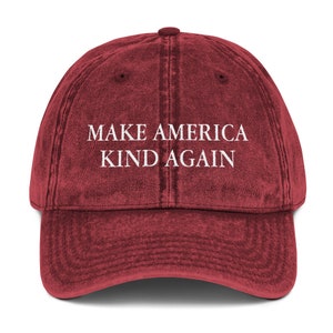 May include: A red vintage baseball cap with the text "Make America Kind Again" embroidered in white.