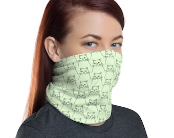 May include: A light green face mask with a repeating pattern of black line drawings of cats. The cats are looking directly at the viewer.