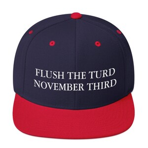 May include: A navy blue and red baseball cap with the text "FLUSH THE TURD NOVEMBER THIRD" embroidered in white.