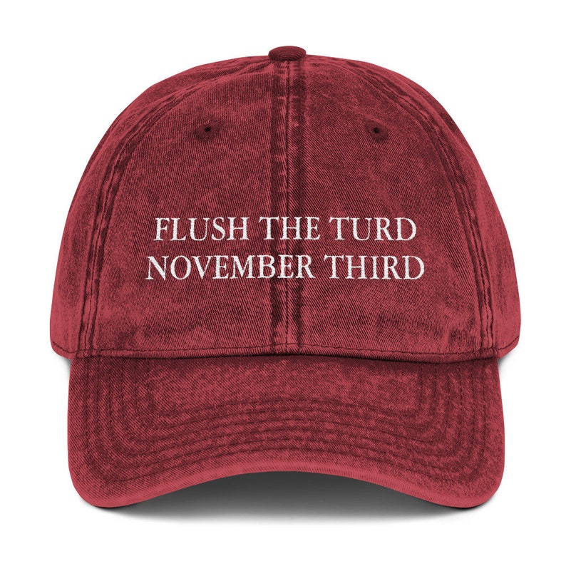 May include: A red vintage style baseball cap with the text "FLUSH THE TURD NOVEMBER THIRD" embroidered in white.