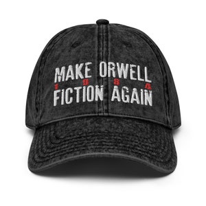 Puede incluir: Gorra de béisbol de denim negro desgastado con texto bordado en blanco que dice "Make Orwell Fiction Again" con los números "1984" en rojo.