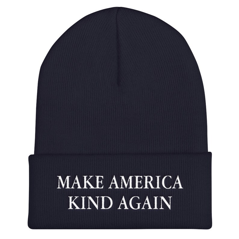 Puede incluir: Un gorro azul marino con el texto "MAKE AMERICA KIND AGAIN" bordado en blanco.