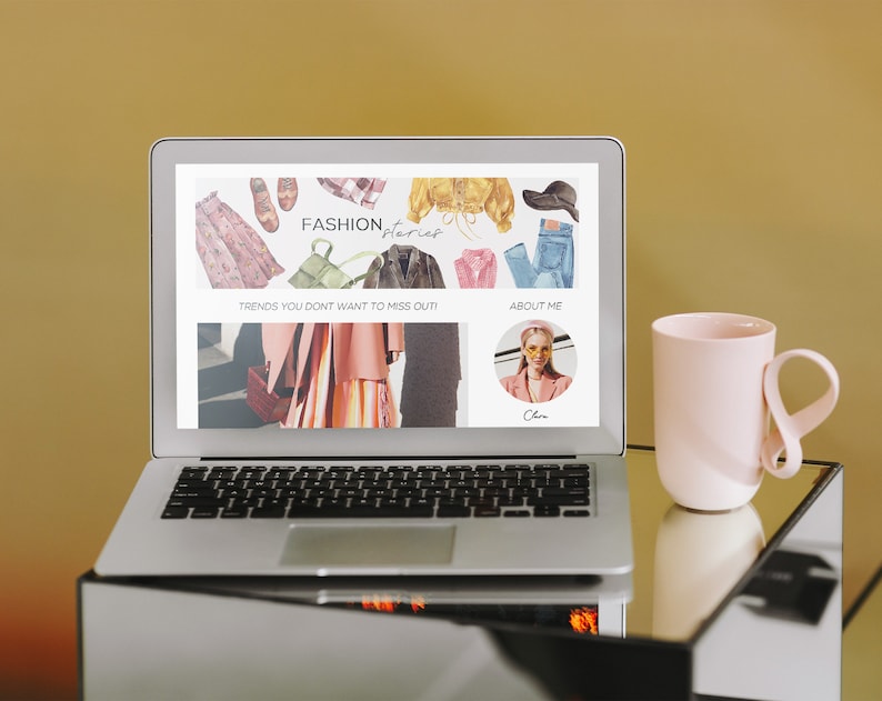Puede incluir: Un ordenador port&aacute;til que muestra un sitio web con el texto "FASHION, Interior" y las palabras "Trends you don't want to miss out!" y "About Me". El sitio web presenta im&aacute;genes de ropa y accesorios. Una taza rosa con un asa &uacute;nica est&aacute; sobre una mesa de vidrio junto al port&aacute;til.