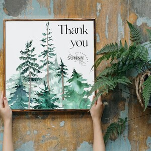 Op de afbeelding: Een ingelijst aquarelprint met een bos sc&egrave;ne van groene bomen en de tekst "Bedankt" en "Zonnig Middag".