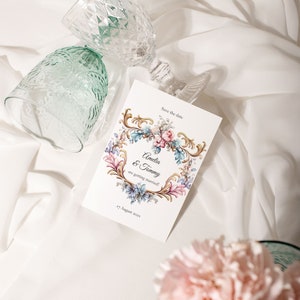 May include: Save the date card with a floral design and gold accents. The card says "Amelia & Tommy are getting married!" and "17 August 2022".