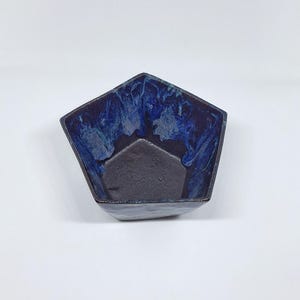 May include: A blue and black ceramic bowl with a five-sided shape. The bowl has a marbled glaze with blue and white swirls.