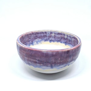 May include: A white ceramic mug with a black handle and the text "But First, Coffee" in a black, bold font. The mug is on a white surface. The mug is approximately 10 cm tall.
