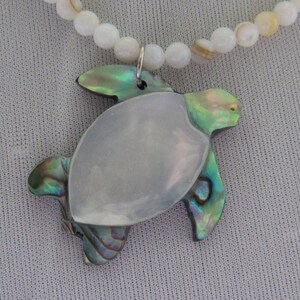 sea turtle created with mother of pearl and abalone on sand colored beaded necklace