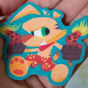 May include: A teal blue sticker featuring a cartoon character with orange fur, holding two flaming torches. The character is wearing a red and orange patterned loincloth and has a fierce expression.