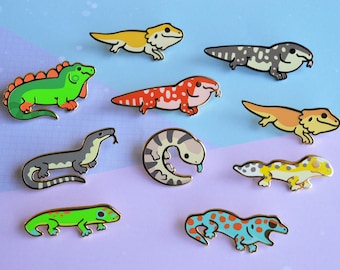 Peut inclure: Dix épingles en émail représentant différents types de lézards, dont un iguane vert, un dragon barbu, un gecko léopard et un gecko à crête. Les épingles sont toutes dorées et ont une finition brillante.