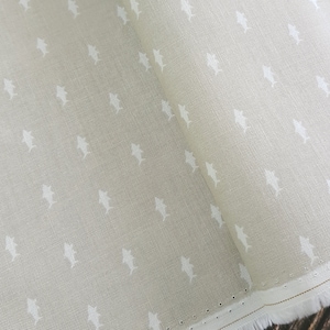 May include: A beige fabric with a white fish pattern. The fabric is folded in half and the edges are visible.