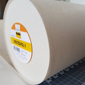 May include: A roll of beige Decovil I interfacing fabric, 35% cotton, 25% viscose, 40% polyester. The label shows the brand name "Vlieseline" and the product name "DECOVIL I".