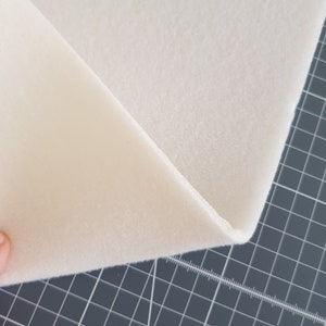 Puede incluir: Primer plano de una l&aacute;mina de espuma blanca, doblada por la mitad, mostrando la textura del material.