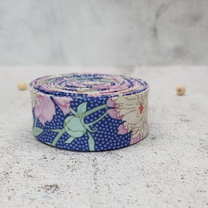 May include: A roll of blue and white floral fabric ribbon with pink flowers and green leaves. The ribbon is rolled up and ready to be used for crafting or decorating.