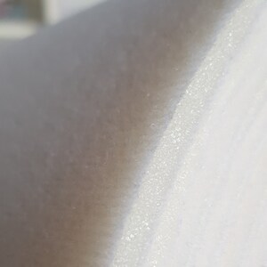 Puede incluir: Primer plano de una tela blanca con una superficie texturizada. La tela tiene un brillo sutil y una sensaci&oacute;n ligeramente &aacute;spera.
