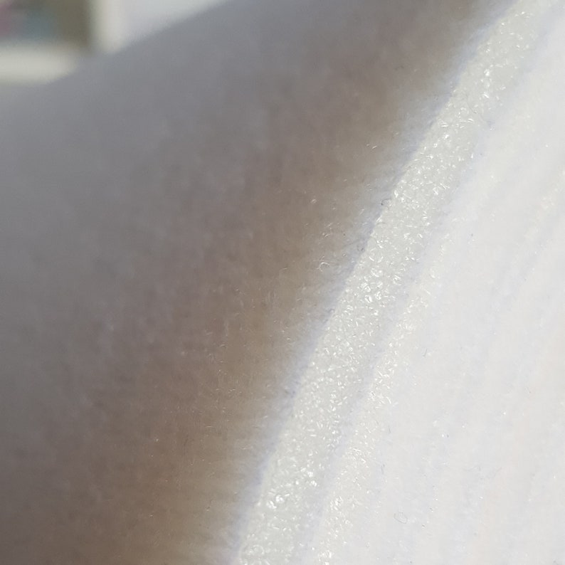 Puede incluir: Primer plano de una tela blanca con una superficie texturizada. La tela tiene un brillo sutil y una sensaci&oacute;n ligeramente &aacute;spera.