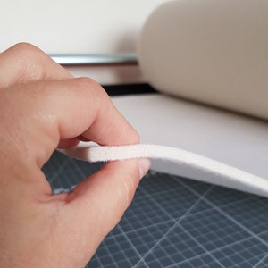 Puede incluir: Primer plano de una l&aacute;mina de espuma blanca que se sostiene con una mano. La espuma es gruesa y tiene una superficie ligeramente texturizada.