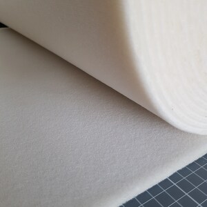 Puede incluir: Primer plano de una l&aacute;mina de espuma blanca enrollada. La espuma es texturizada y tiene un aspecto ligeramente granulado.