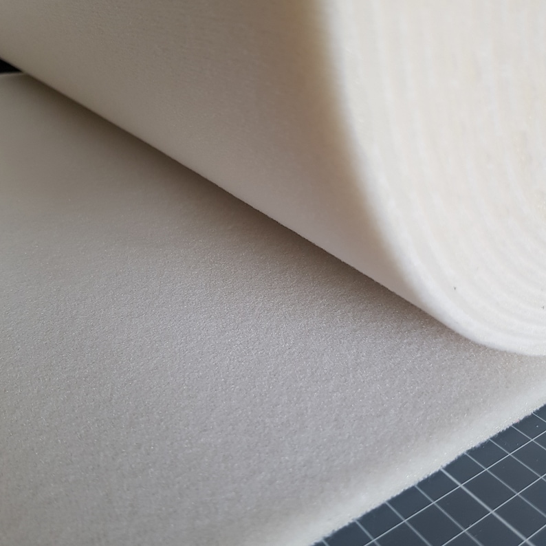 Puede incluir: Primer plano de una l&aacute;mina de espuma blanca enrollada. La espuma es texturizada y tiene un aspecto ligeramente granulado.