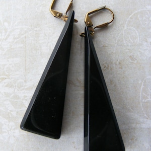 May include: A pair of black triangle-shaped earrings with gold-toned leverback fastenings.