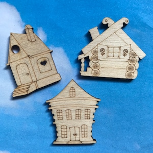 May include: Three wooden house cutouts, each with a different design. The first house is a simple, one-story house with a heart-shaped window. The second house is a log cabin with a porch and a window with flowers. The third house is a two-story house with four windows and a door.